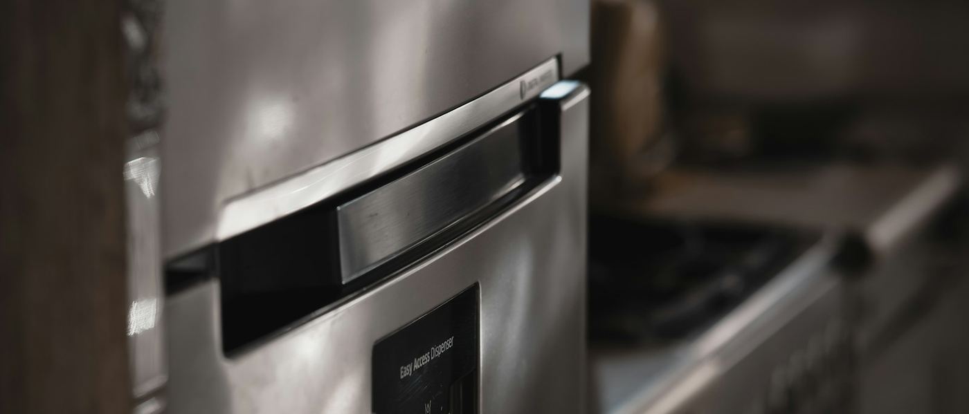Close-up of a stainless steel built-in refrigerator beside a range in a premium kitchen